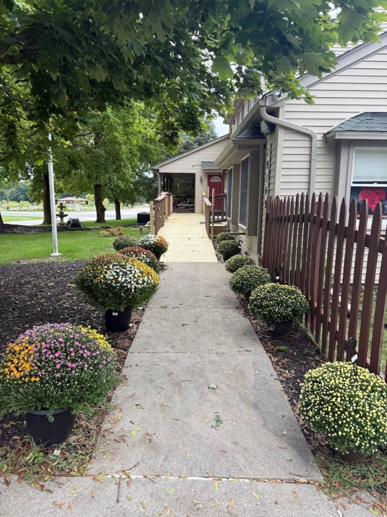 Sunny Pointe Childcare Center on Fry Road in Northville, MI — tree-shaded entrance walkway with fall mums