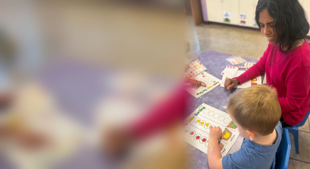 Sunny Pointe teacher helping a preschooler with an apple color-sorting activity in Northville