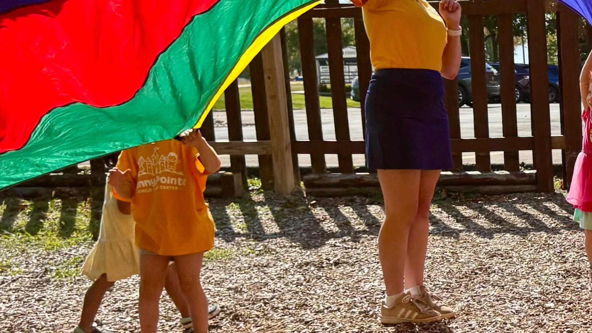 Kids playing parachute games outside at Sunny Pointe Childcare Center in Northville