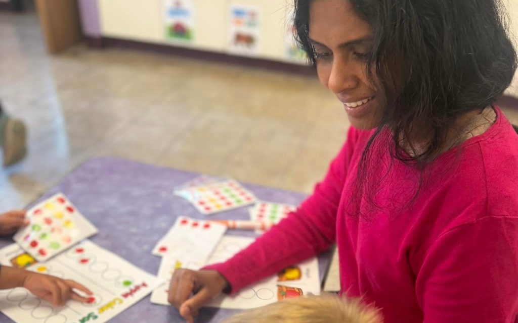 Teacher helping a preschooler with a color-sorting activity at Sunny Pointe in Northville